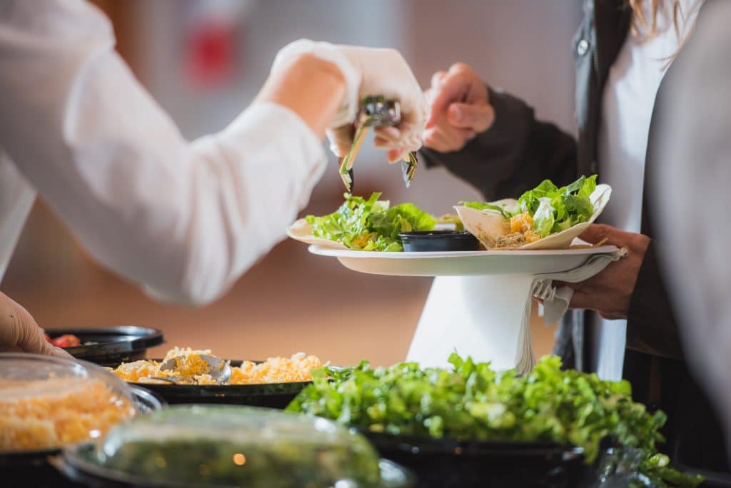 A buffet scene where one person is offering food to another, emphasizing the sharing of meals.