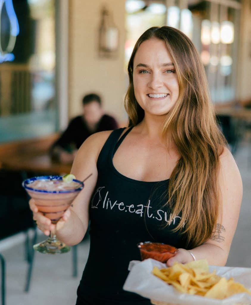 A Tower7 waitress serving a margarita, chips, and salsa.