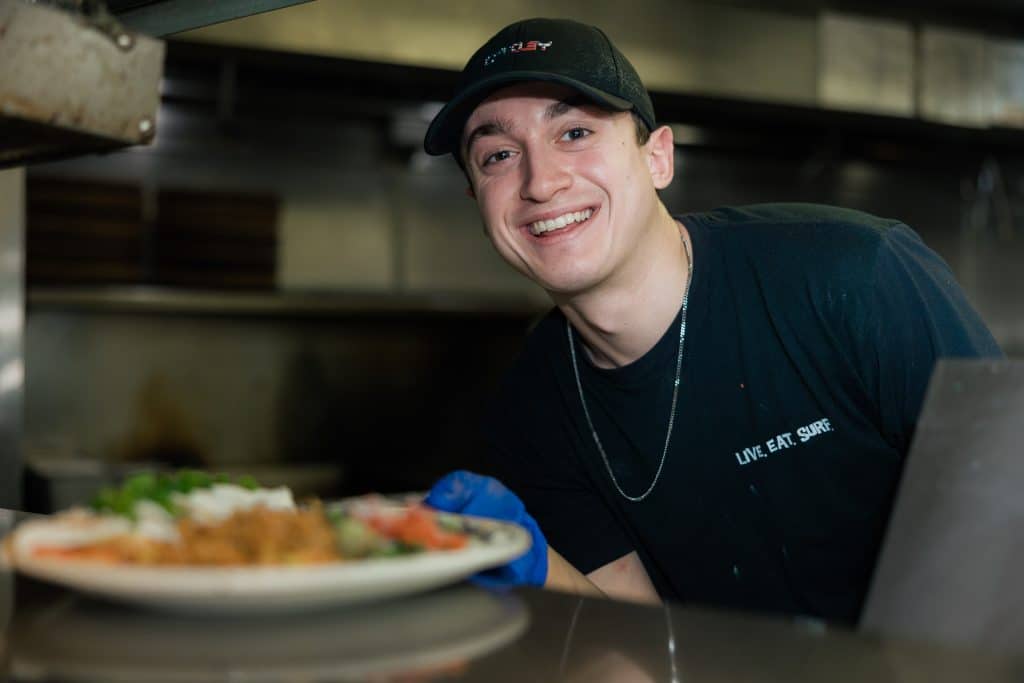 A Tower7 cook presenting a plate of food.